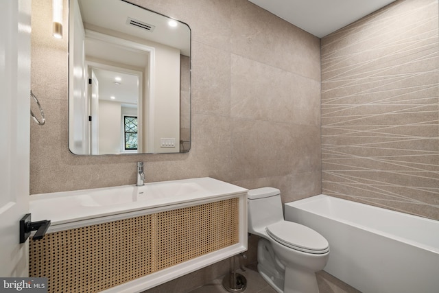 bathroom featuring toilet, vanity, tile walls, and a tub