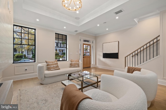 living room featuring light wood-type flooring, ornamental molding, and a raised ceiling