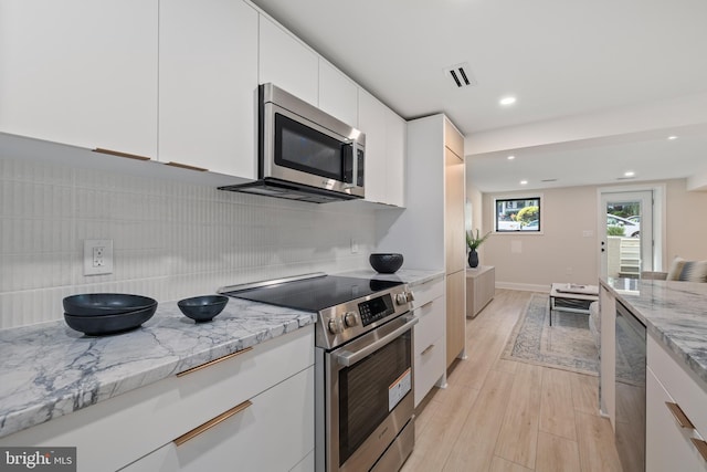 kitchen with stainless steel appliances, light stone counters, tasteful backsplash, white cabinetry, and light hardwood / wood-style flooring