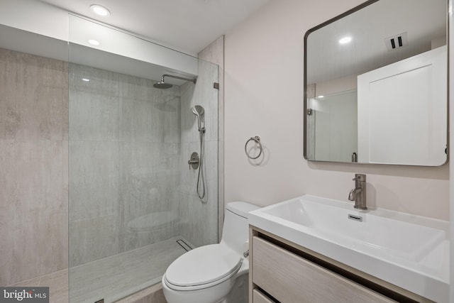 bathroom featuring toilet, vanity, and a tile shower