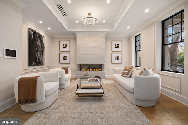 living room with ornamental molding, hardwood / wood-style floors, and a tiled fireplace