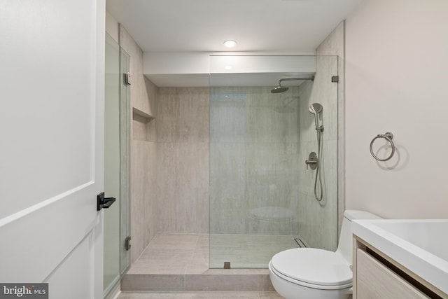 bathroom featuring toilet, vanity, tile patterned flooring, and a shower with shower door