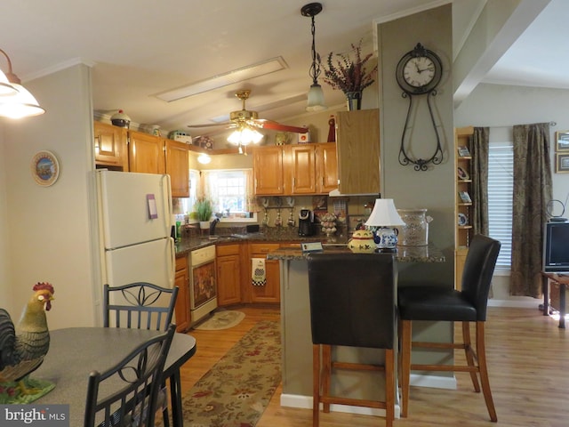 kitchen featuring white appliances, light hardwood / wood-style flooring, vaulted ceiling, and decorative light fixtures