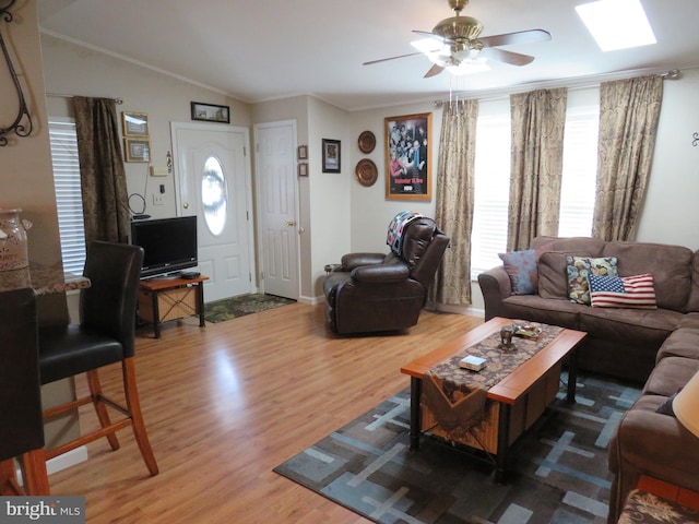 living room featuring ceiling fan, wood-type flooring, crown molding, and vaulted ceiling