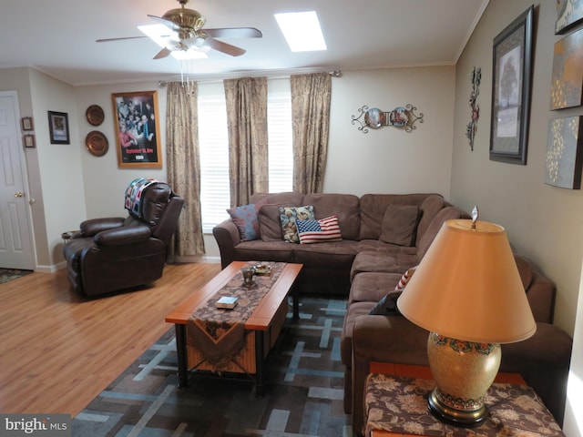 living room featuring ornamental molding, a skylight, wood-type flooring, and ceiling fan