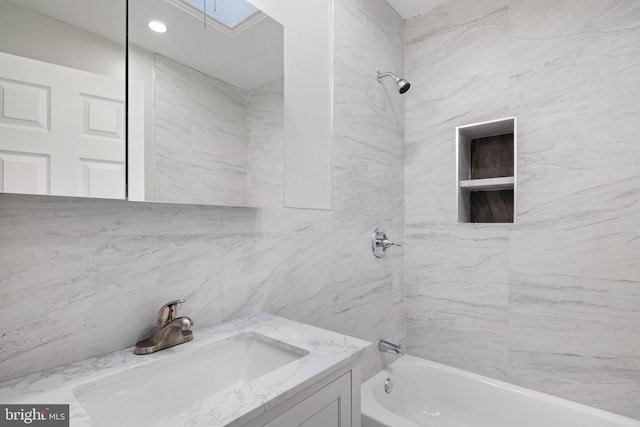 bathroom featuring tiled shower / bath combo, tile walls, and vanity