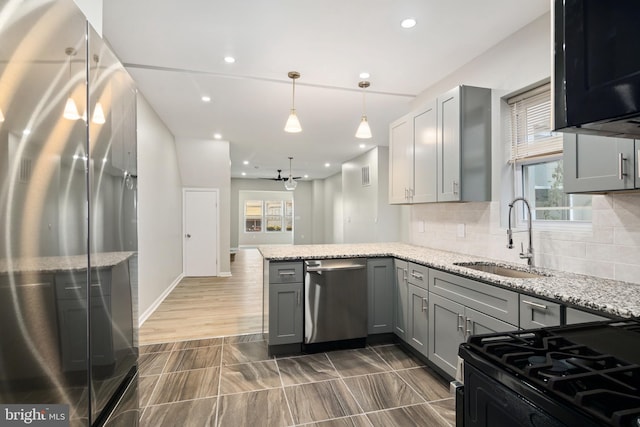 kitchen with kitchen peninsula, appliances with stainless steel finishes, gray cabinetry, and sink