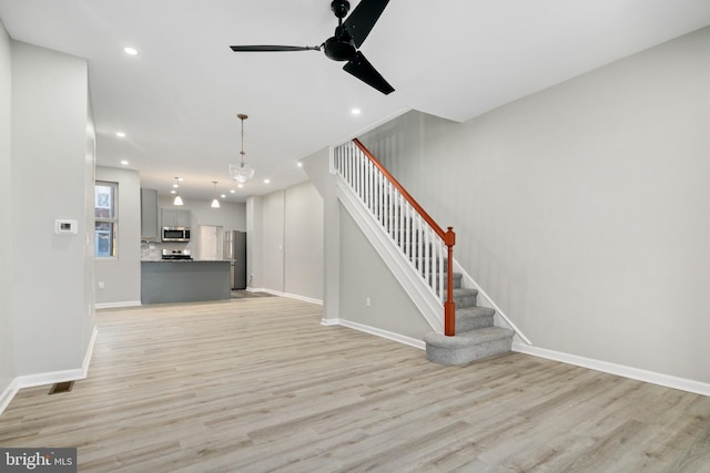 unfurnished living room with light hardwood / wood-style floors and ceiling fan with notable chandelier