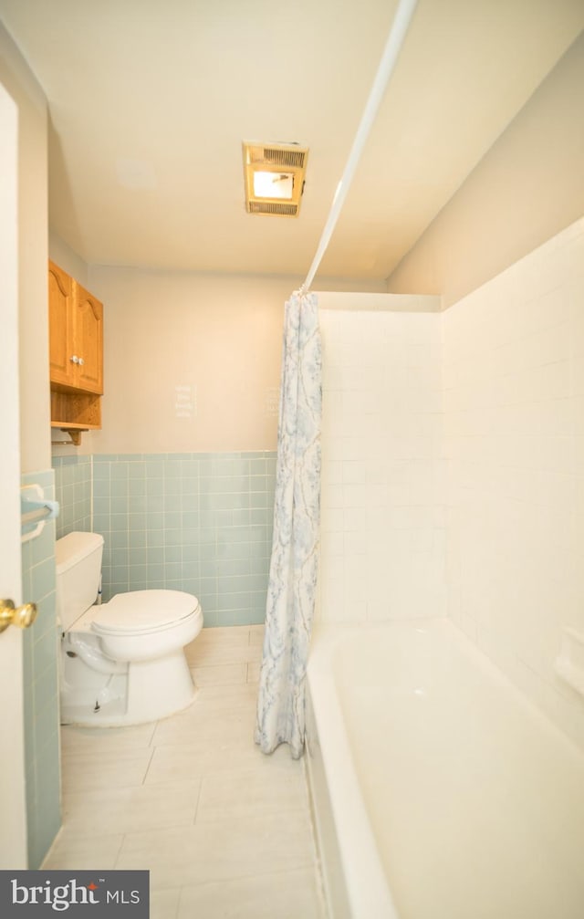 bathroom with tile walls, tile patterned floors, toilet, and shower / bathtub combination with curtain