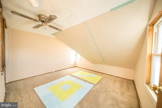 additional living space with light carpet, a textured ceiling, lofted ceiling, and ceiling fan