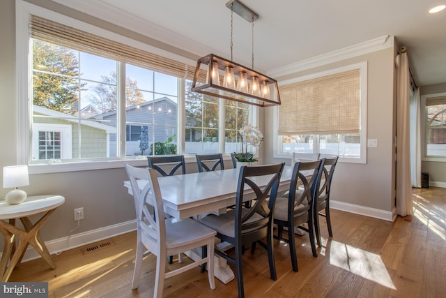 dining space featuring crown molding, hardwood / wood-style flooring, a chandelier, and plenty of natural light