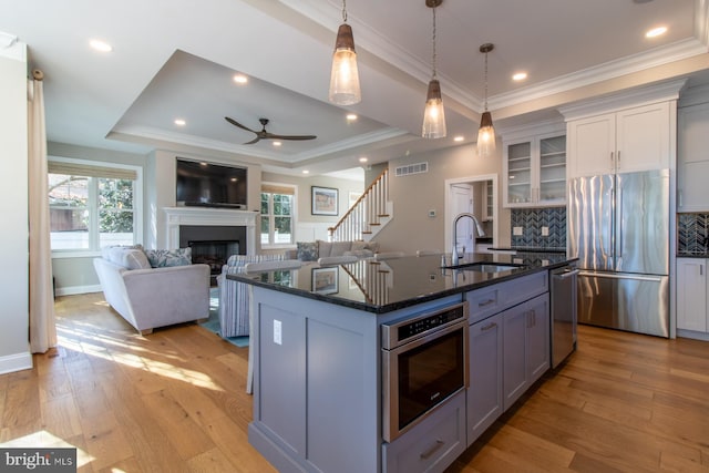 kitchen featuring appliances with stainless steel finishes, light hardwood / wood-style flooring, a kitchen island with sink, and a wealth of natural light