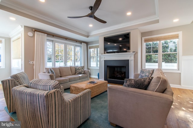 living room featuring dark wood-type flooring, crown molding, plenty of natural light, and ceiling fan