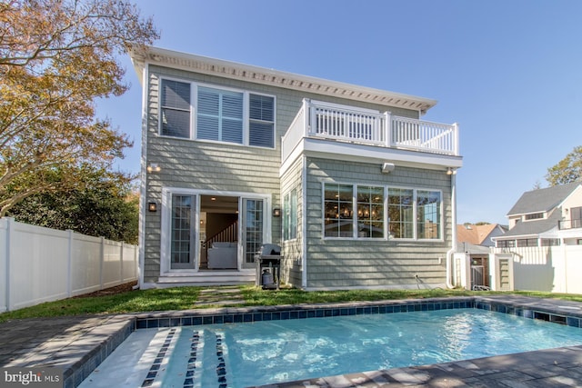 back of house with a fenced in pool and a balcony