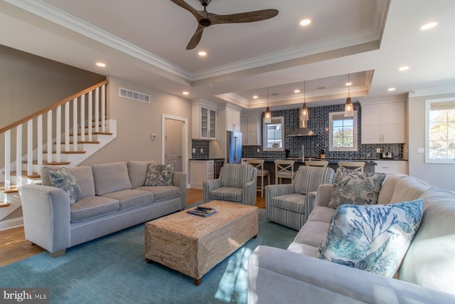 living room with ornamental molding, a tray ceiling, and dark hardwood / wood-style floors