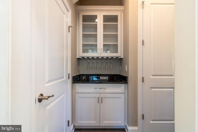 bar featuring white cabinetry and dark stone counters