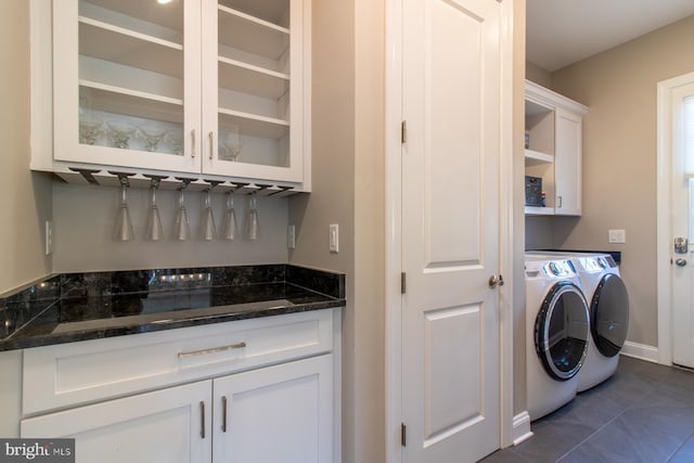 clothes washing area featuring independent washer and dryer, dark tile patterned flooring, and cabinets