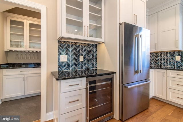 kitchen with decorative backsplash, beverage cooler, white cabinetry, high quality fridge, and light hardwood / wood-style floors