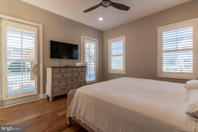 bedroom with hardwood / wood-style floors, multiple windows, access to exterior, and ceiling fan