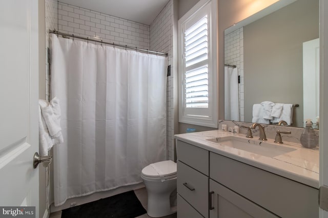 bathroom with vanity, curtained shower, toilet, and a wealth of natural light