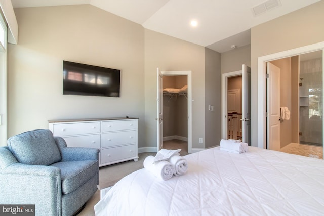 bedroom with light carpet, lofted ceiling, a spacious closet, ensuite bathroom, and a closet