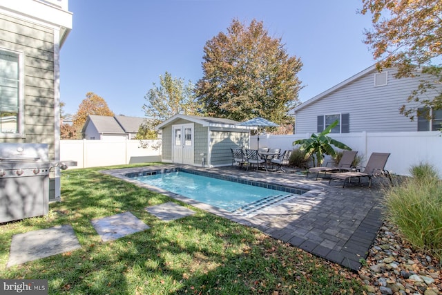 view of pool with a patio, an outbuilding, and a lawn