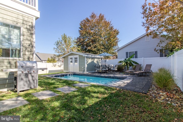 view of pool featuring a patio, an outdoor structure, grilling area, and a lawn