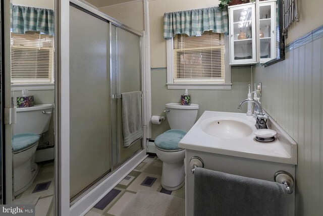 bathroom featuring vanity, a shower with shower door, and toilet