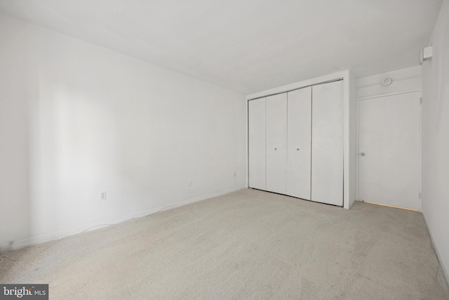 unfurnished bedroom with light carpet and a closet