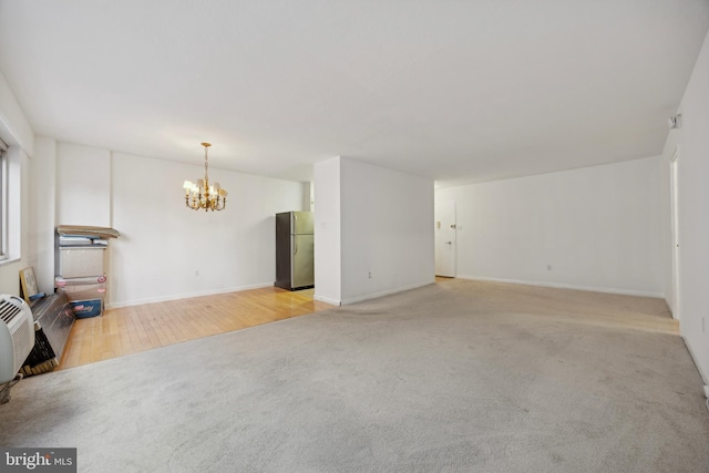 spare room with an inviting chandelier and light hardwood / wood-style flooring