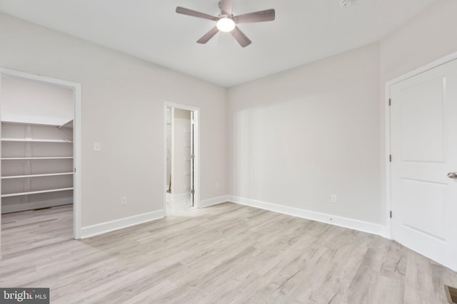 unfurnished bedroom featuring light hardwood / wood-style floors, ceiling fan, a walk in closet, and a closet