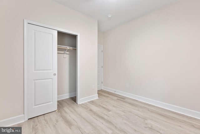 unfurnished bedroom featuring light hardwood / wood-style flooring and a closet