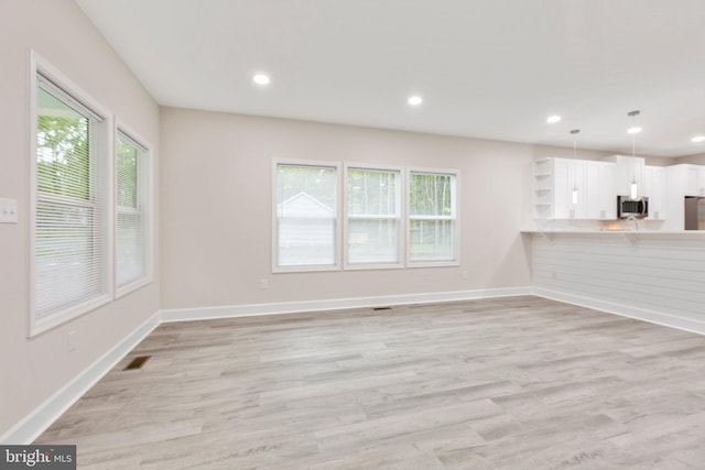 unfurnished living room with a healthy amount of sunlight and light hardwood / wood-style flooring