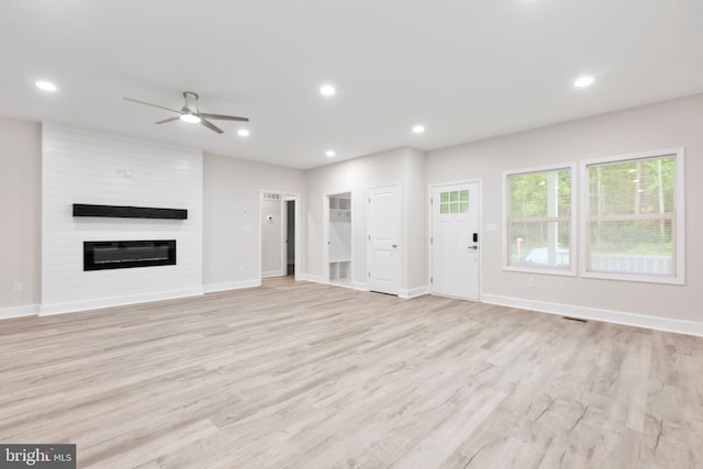 unfurnished living room featuring a fireplace, ceiling fan, and light hardwood / wood-style flooring