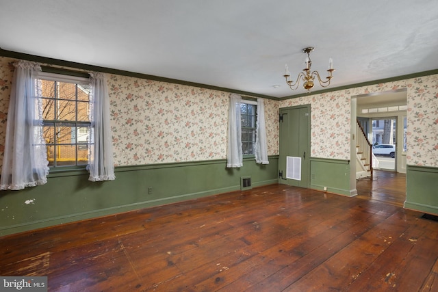 spare room with ornamental molding, dark hardwood / wood-style floors, and a chandelier