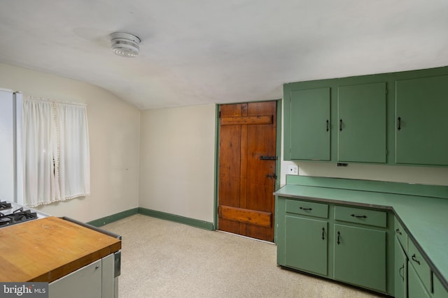 kitchen with wooden counters, vaulted ceiling, light colored carpet, and green cabinetry