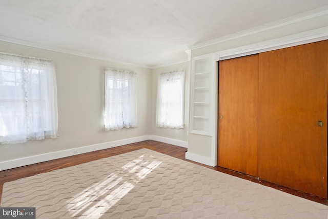 unfurnished bedroom featuring a closet, hardwood / wood-style floors, and crown molding