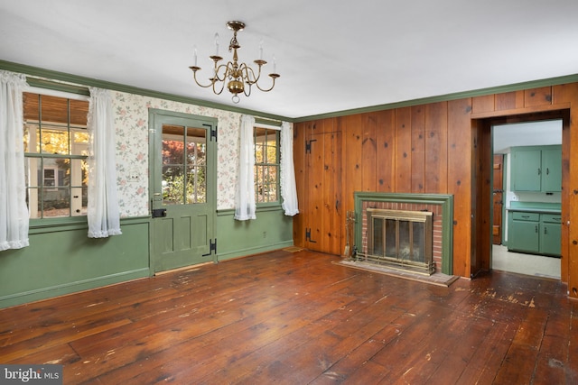 unfurnished living room with dark hardwood / wood-style flooring, an inviting chandelier, ornamental molding, and a fireplace