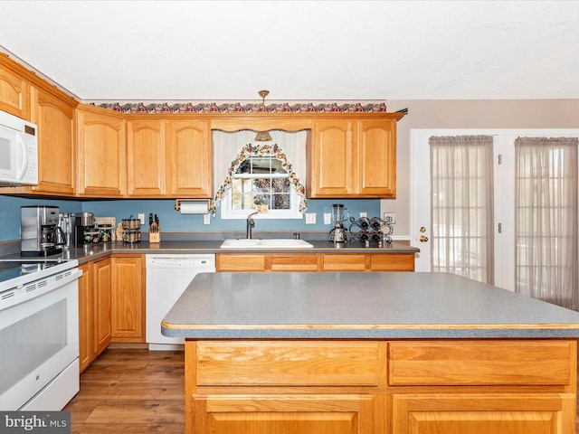 kitchen featuring light wood-type flooring, a center island, sink, and white appliances