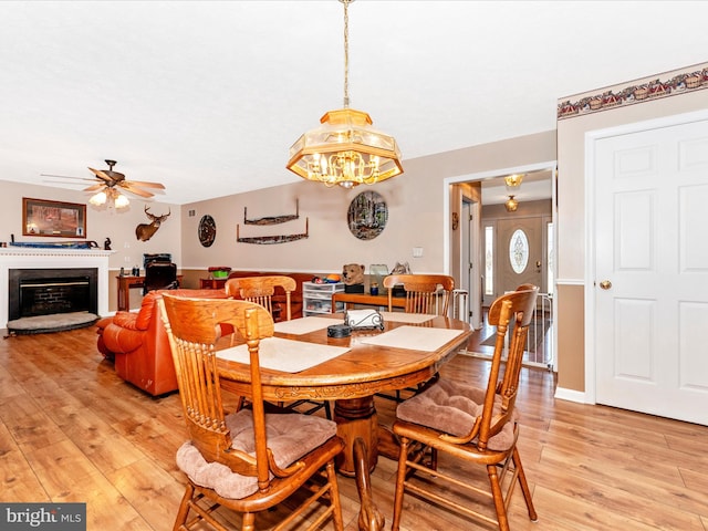 dining area featuring light wood-type flooring and ceiling fan with notable chandelier