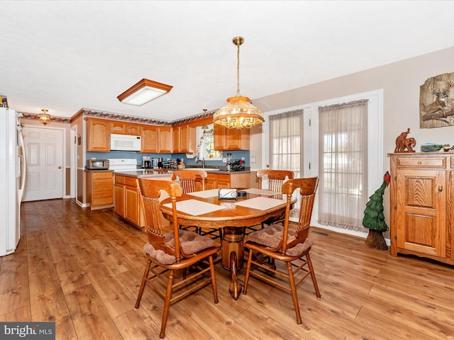 dining area with light hardwood / wood-style flooring, sink, and an inviting chandelier