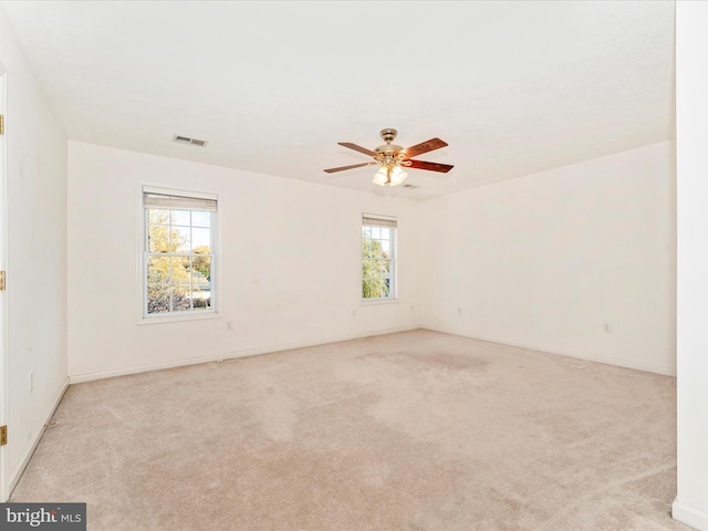 unfurnished room featuring a wealth of natural light, light carpet, and ceiling fan