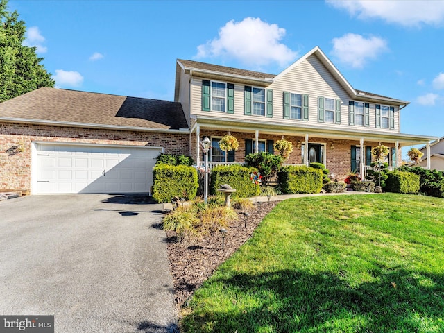 view of front of property with covered porch, a garage, and a front yard