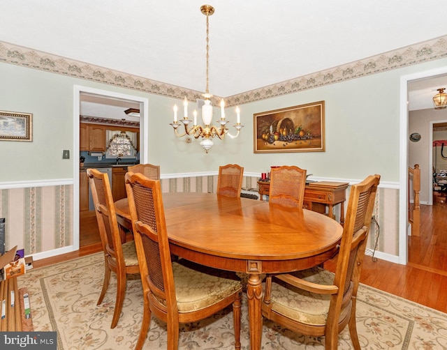 dining room with light wood-type flooring and an inviting chandelier