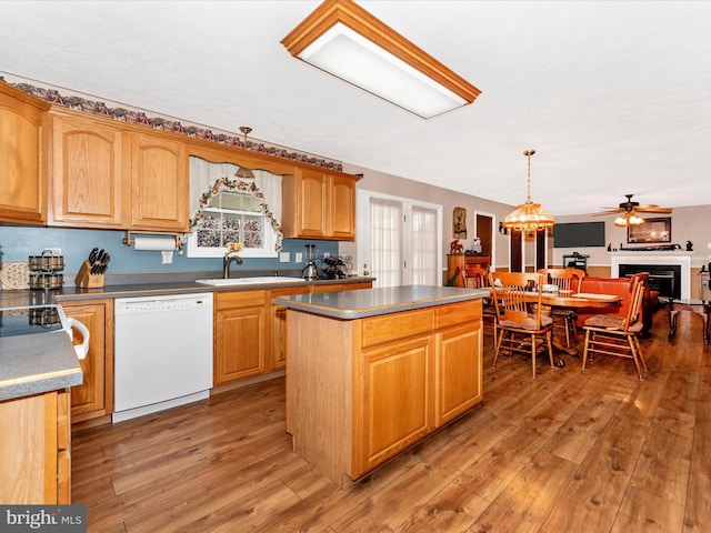 kitchen with dark wood-type flooring, a kitchen island, pendant lighting, sink, and dishwasher