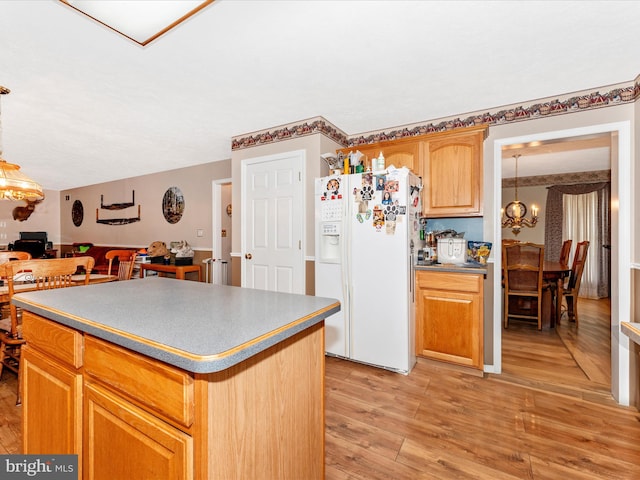 kitchen featuring a center island, a notable chandelier, white refrigerator with ice dispenser, pendant lighting, and light wood-type flooring