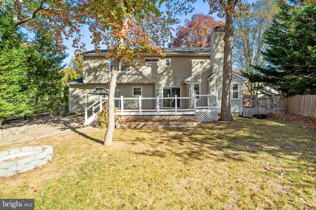 rear view of house featuring a wooden deck and a lawn