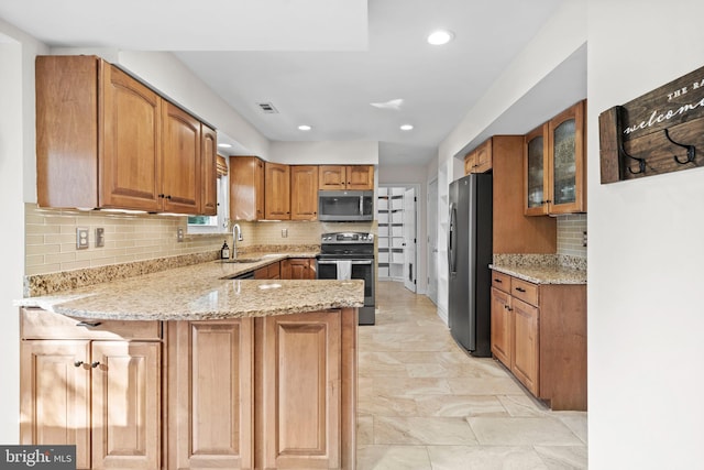 kitchen with light stone countertops, sink, kitchen peninsula, decorative backsplash, and appliances with stainless steel finishes