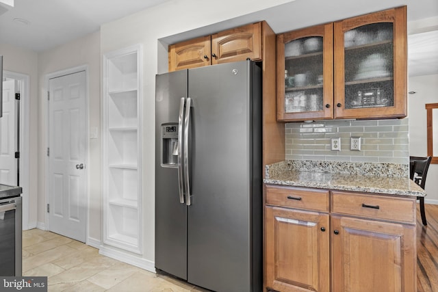 kitchen with stainless steel fridge, light stone countertops, backsplash, and light tile patterned floors