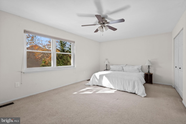 bedroom with light colored carpet, a closet, and ceiling fan